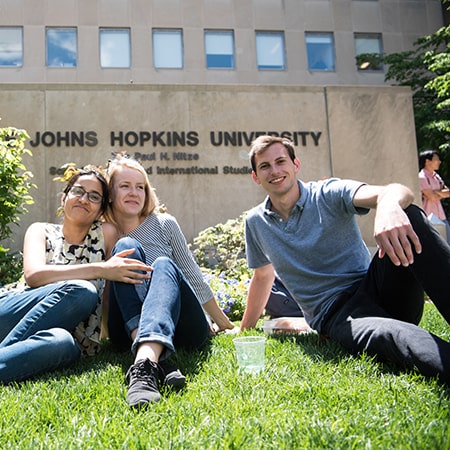 Johns Hopkins SAIS students sitting on the front lawn of the Nitze Building