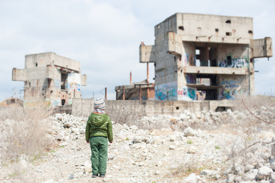 A child stands among bombed-out buildings in Syria.