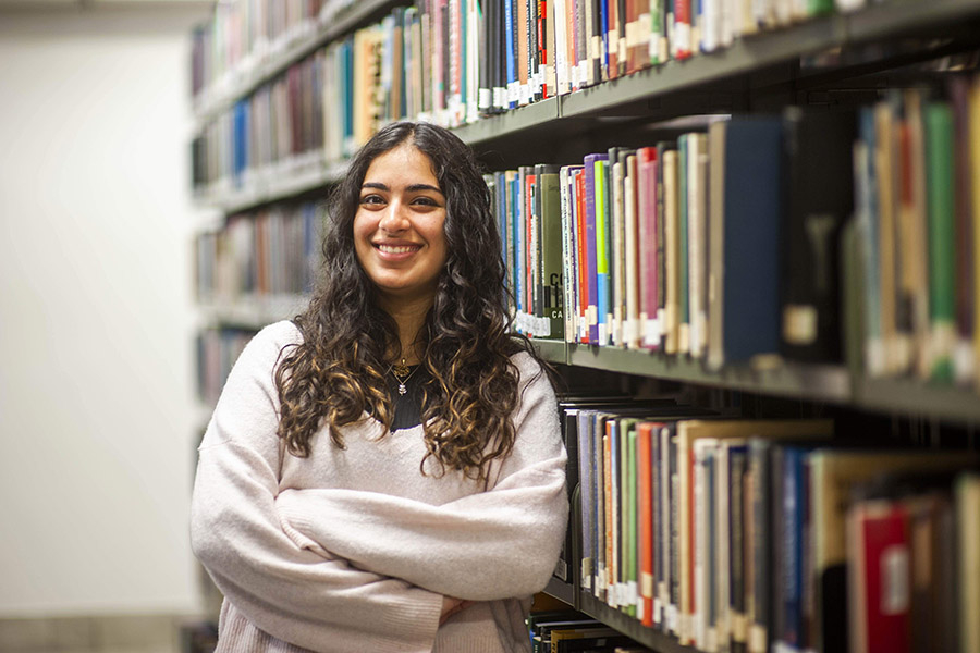 A Johns Hopkins SAIS student standing in front of a bookcase. 